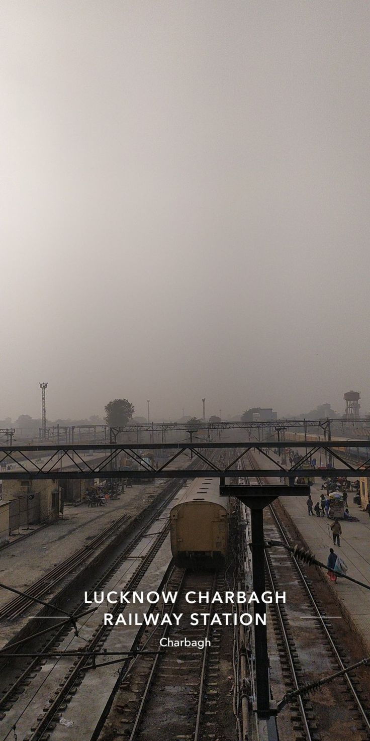 the train is traveling down the tracks on a foggy day with people walking around