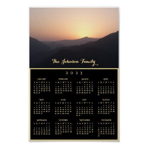 a calendar with the sun setting in the distance and mountains behind it, on a black background