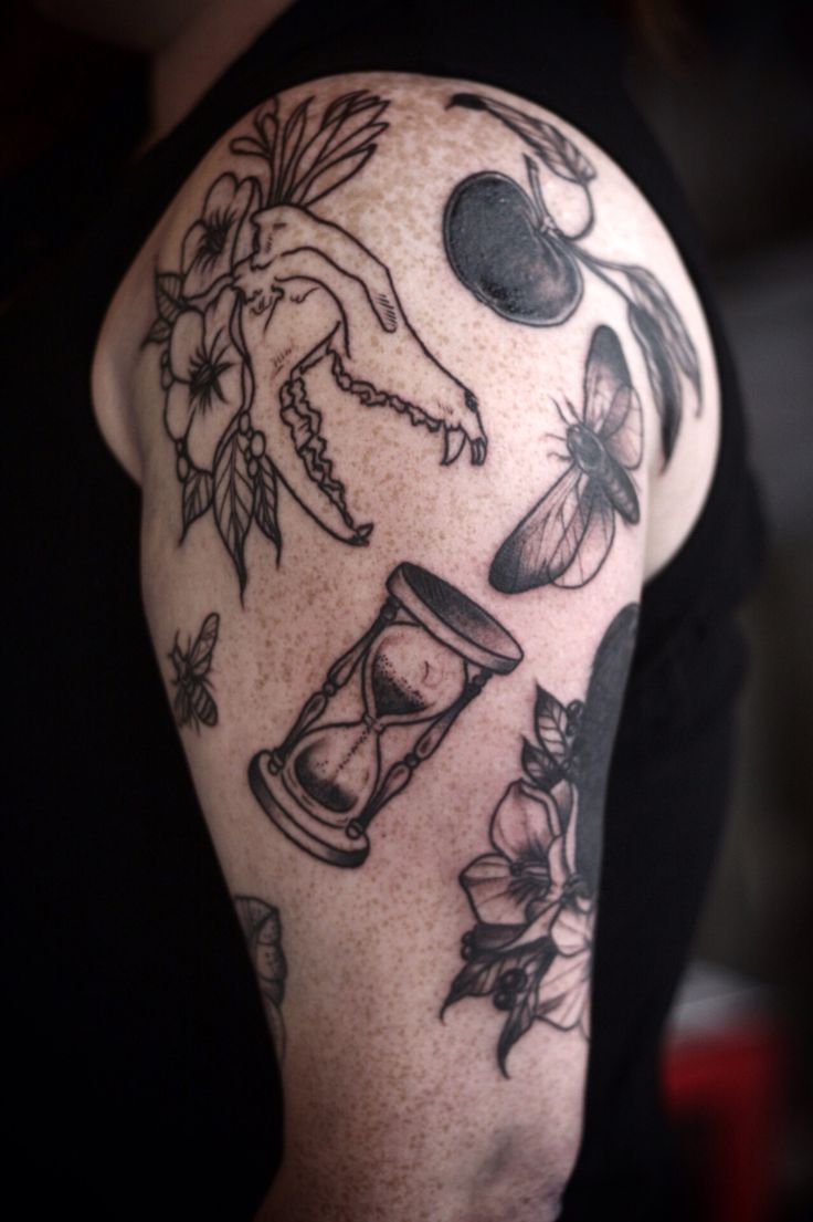 a man's arm with tattoos on it, including an hourglass and flowers