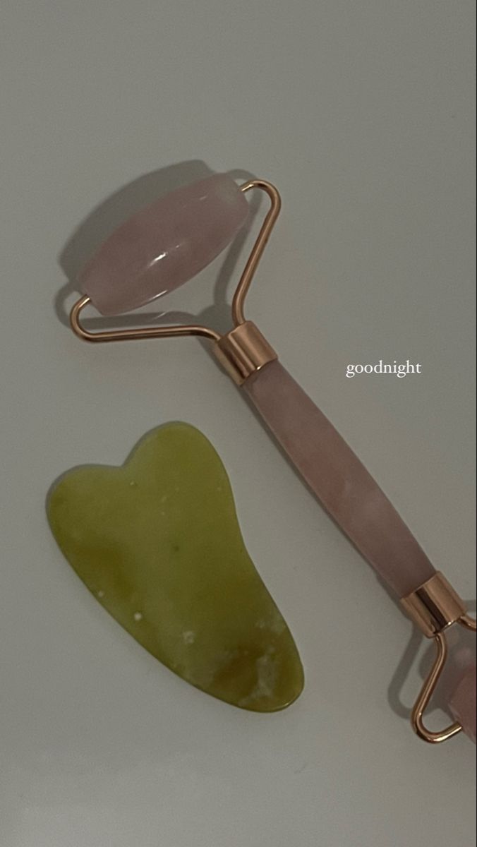 a green heart shaped object sitting next to a gold handled utensil on a white surface