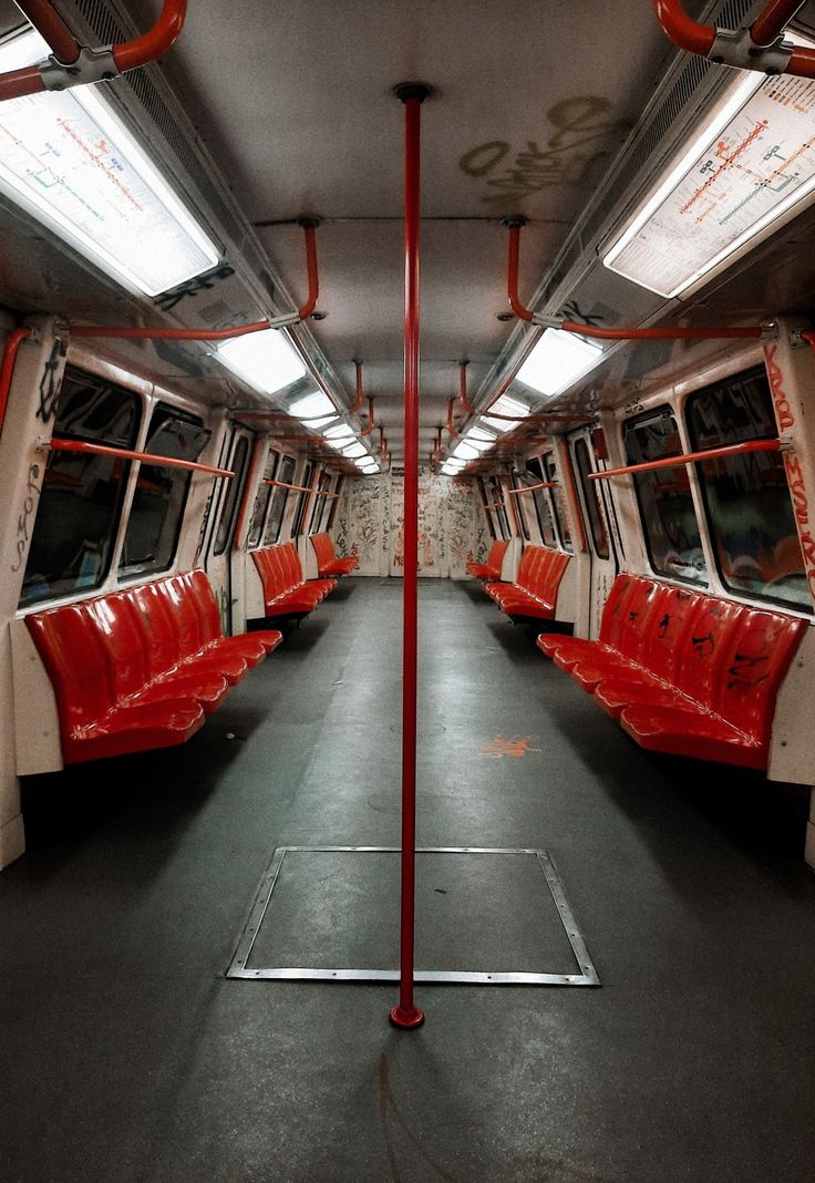 the inside of a subway car with red seats and lights on each side of it