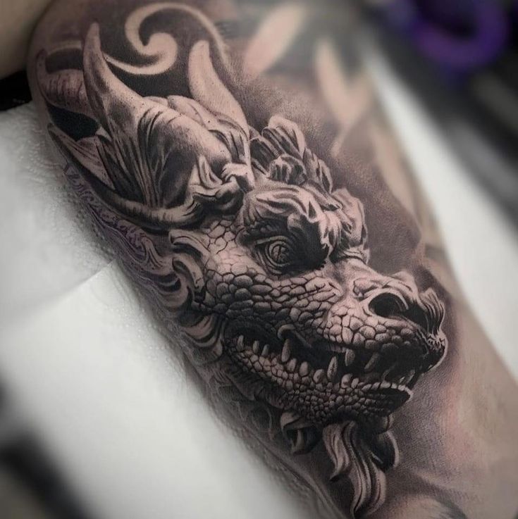 a black and white tattoo of a dragon on the arm