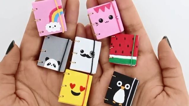 four small notebooks in the shape of animals are held by someone's hands