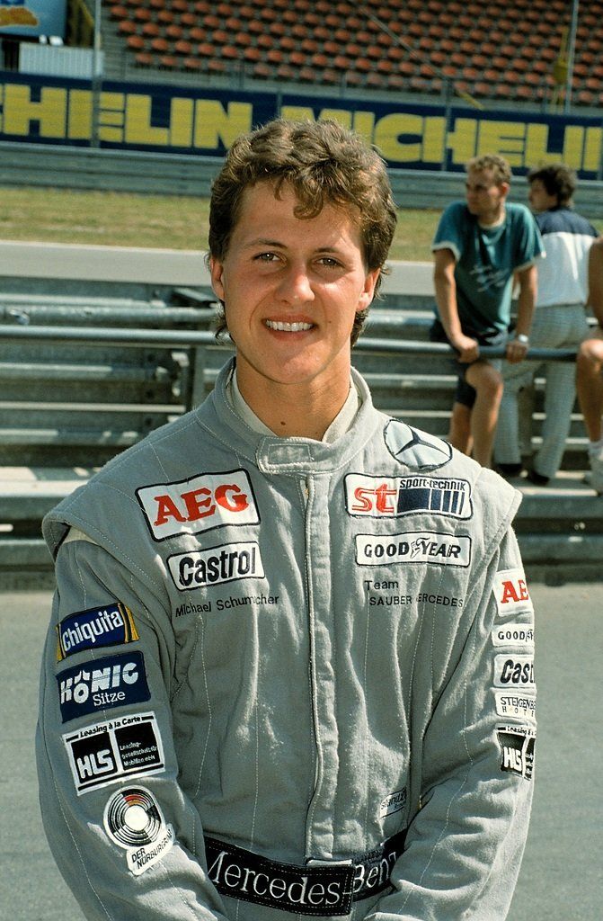 a man standing in front of a race track with his hands on his hips and two men sitting behind him