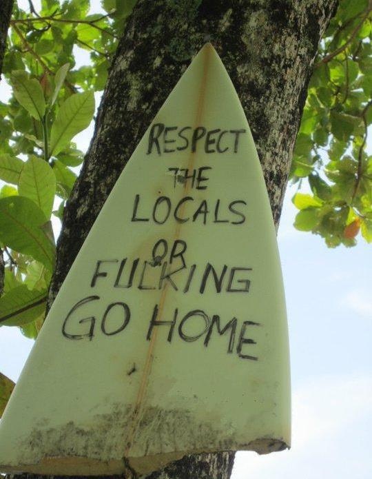 a surfboard that has been placed on the side of a tree with graffiti written on it