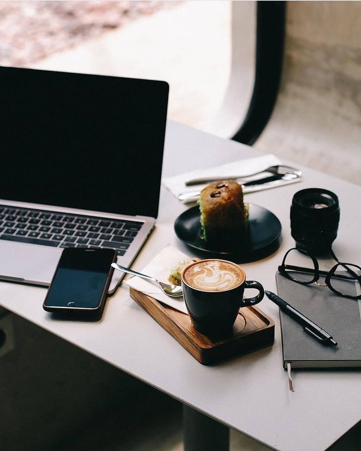 a laptop computer sitting on top of a white table next to a cup of coffee