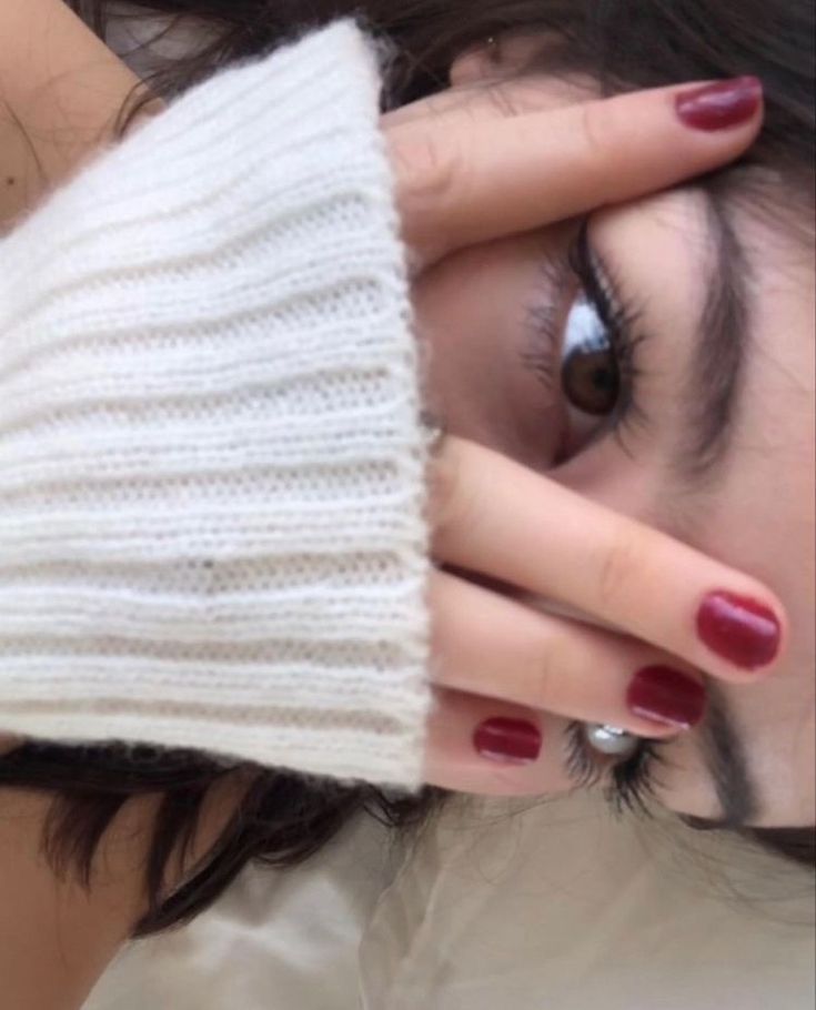 a close up of a person covering their face with her hand and holding the top half of her eye