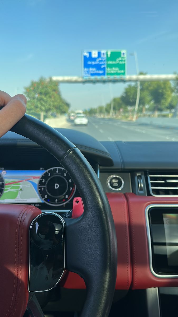 the steering wheel of a car with a map on it's display screen in front of a highway sign