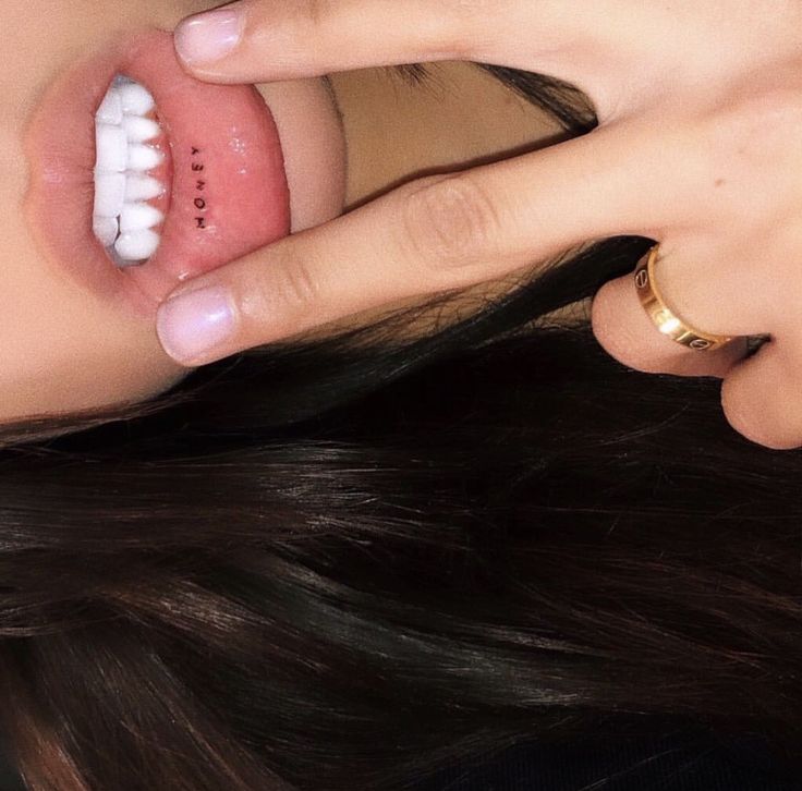 a close up of a person holding their hand near her mouth with teeth on it