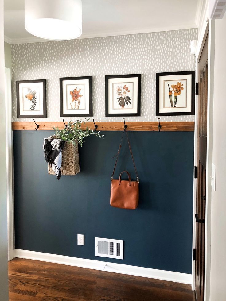 a blue wall with pictures on it and a brown bag hanging from the hooks in front