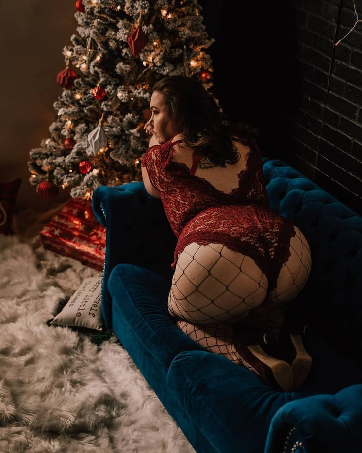 a woman sitting on top of a blue couch in front of a christmas tree with stockings