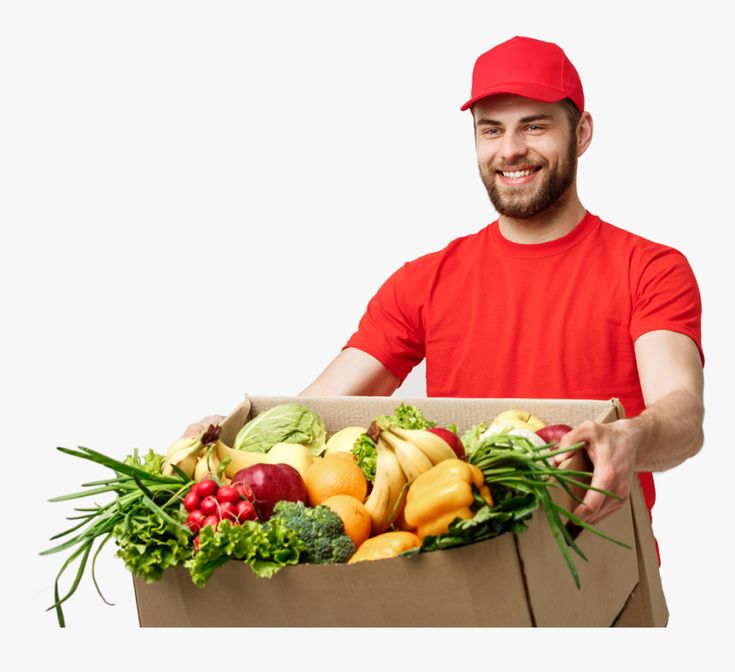 a man holding a cardboard box filled with lots of fruit and vegtables