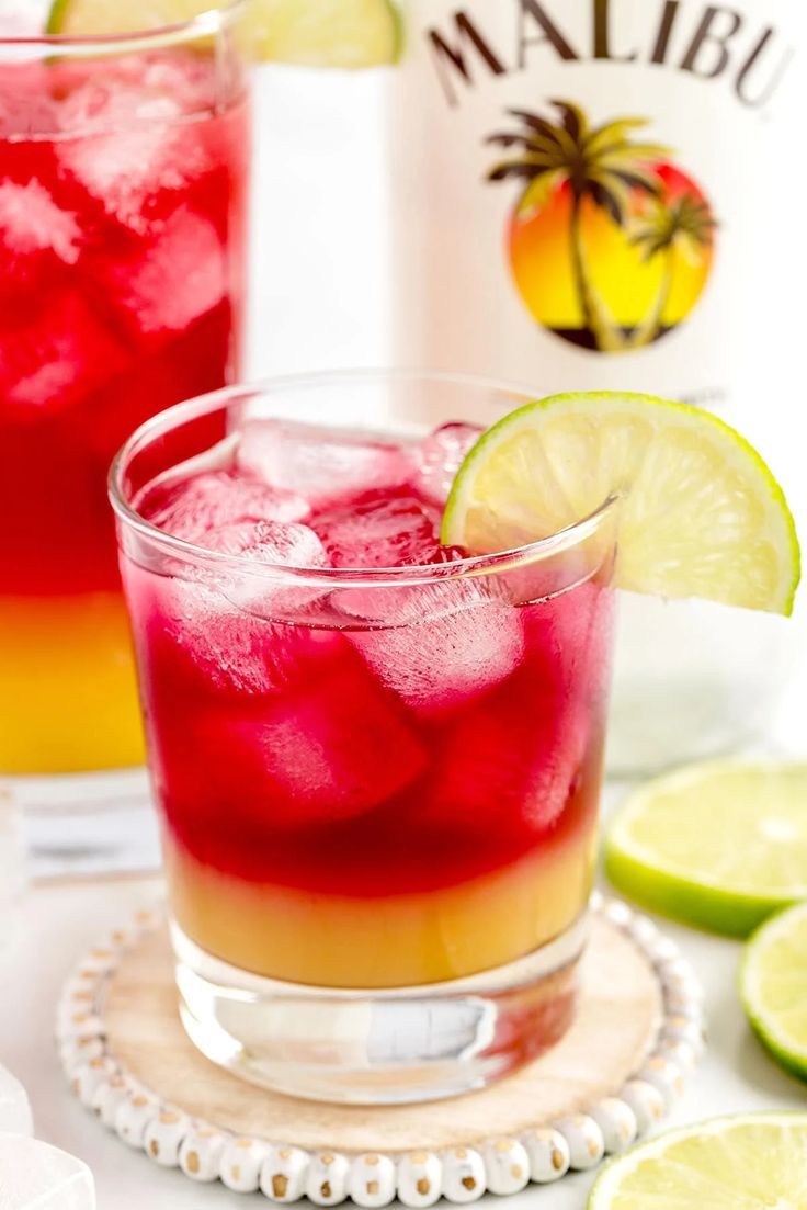 two glasses filled with watermelon and limeade next to a spoon on a white surface