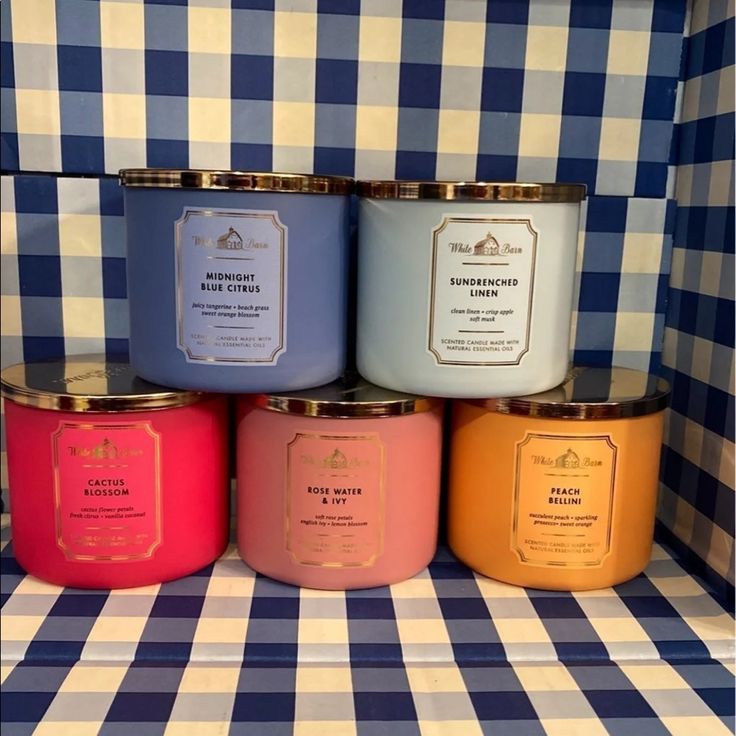 four different colored candles sitting on top of a checkered table cloth