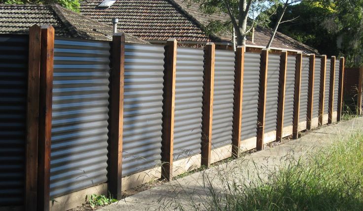 a fence made out of metal slats next to a house