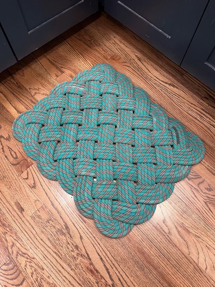 a blue and green rug on the floor in front of black cabinets with wooden floors