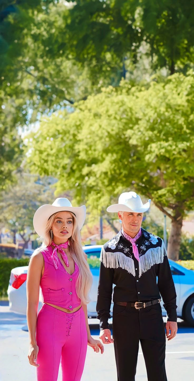 a man and woman in cowboy hats standing next to each other on the side of the road