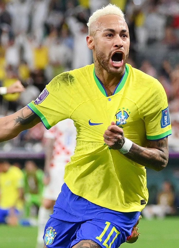 a soccer player with his mouth wide open in front of the camera and fans behind him