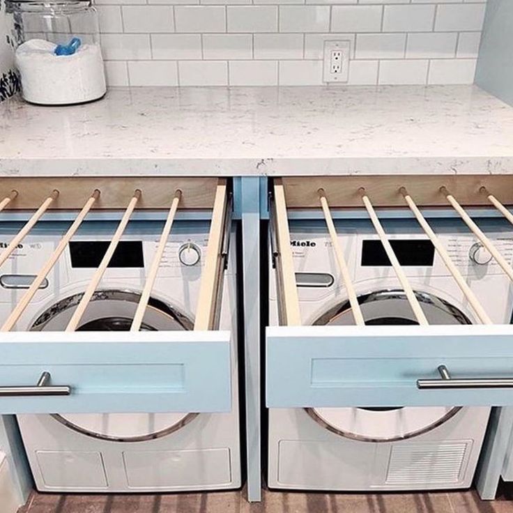 two washers and dryer in a kitchen with white tile backsplashes