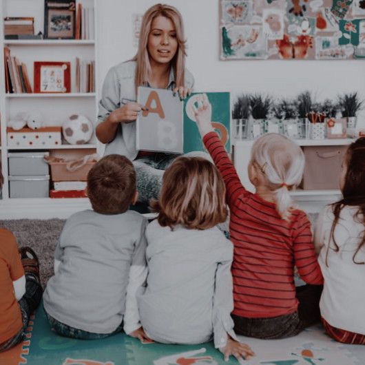 a woman reading to children sitting on the floor