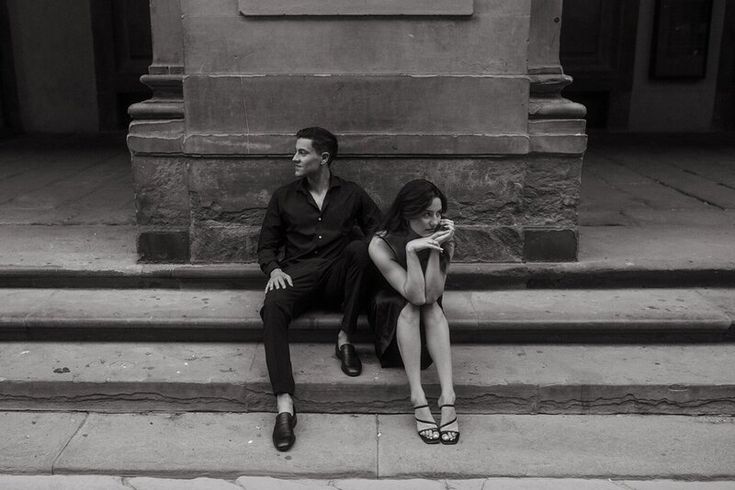 black and white photograph of two people sitting on steps