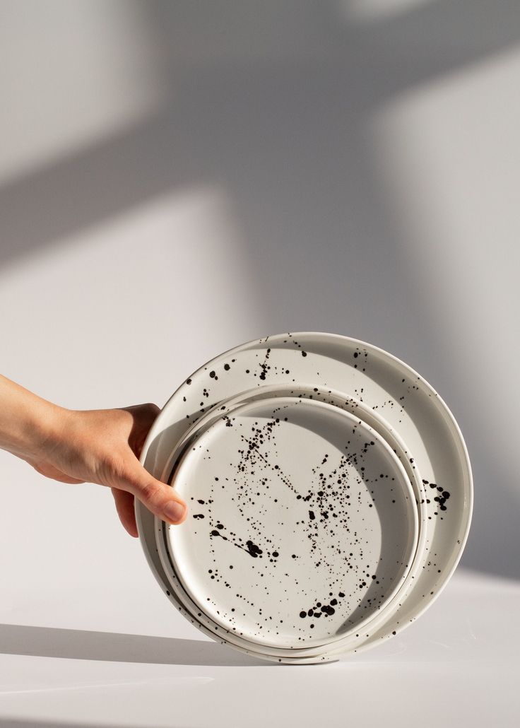 a person holding a white plate with black spots on it