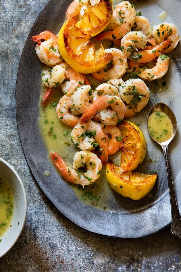 a plate filled with shrimp and squash on top of a table next to a bowl of sauce