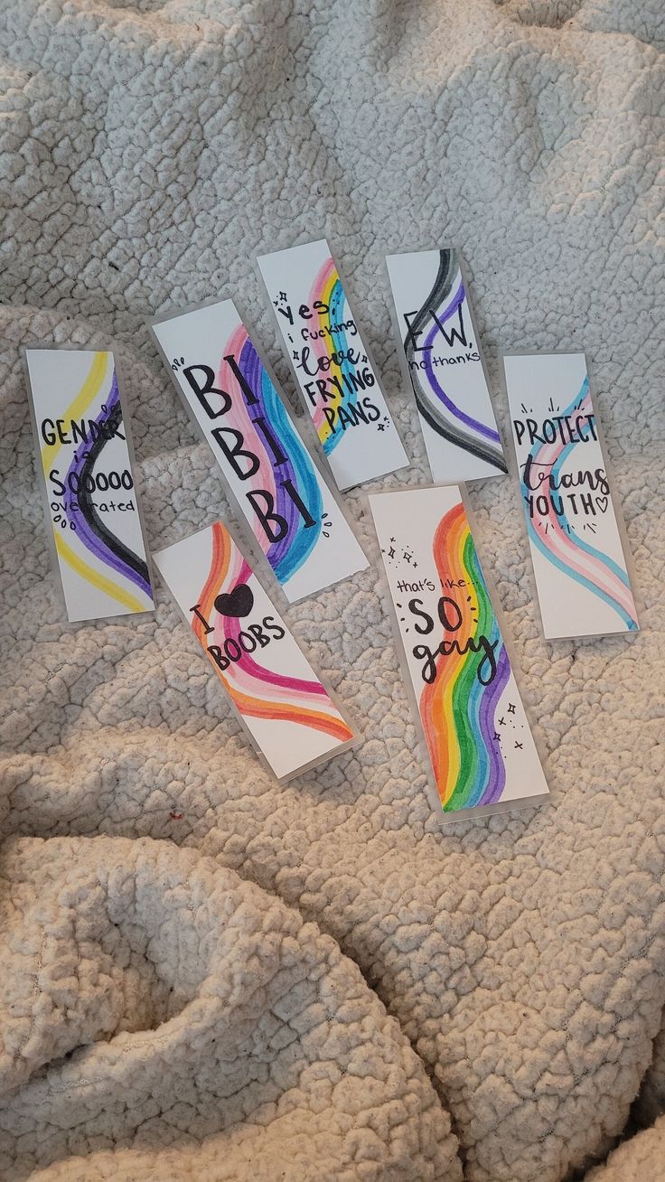 four tags with different colors and designs on a white blanket that has been folded over