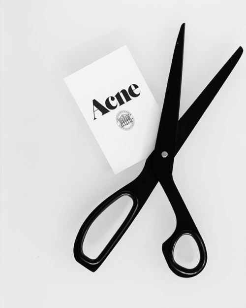 a pair of black scissors sitting on top of a white table next to a paper