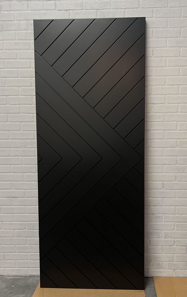 a black door sitting on top of a wooden floor next to a white brick wall