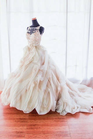 a wedding dress is displayed on a mannequin in front of a window with sheer curtains