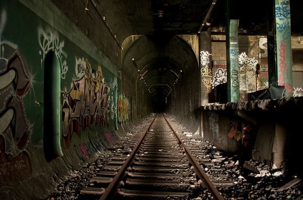 a train track going through a tunnel with graffiti on the walls