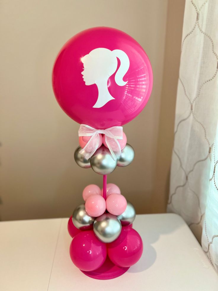 a pink balloon with a woman's head on top of it sitting on a table