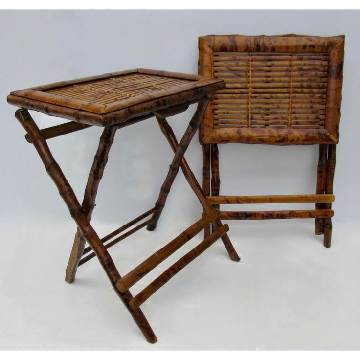 two wooden chairs and a small table made out of bamboo sticks, one with a tray on it