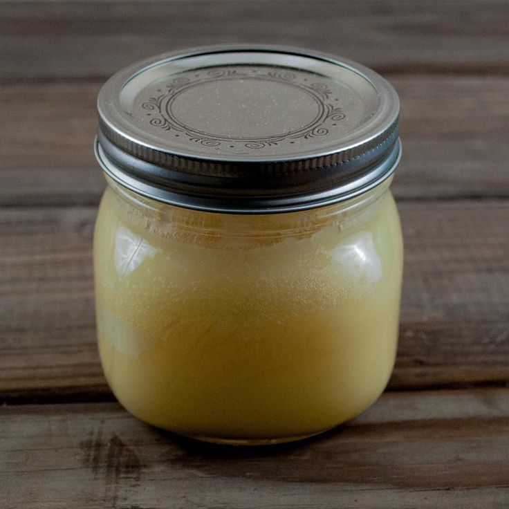 a jar filled with yellow liquid sitting on top of a wooden table