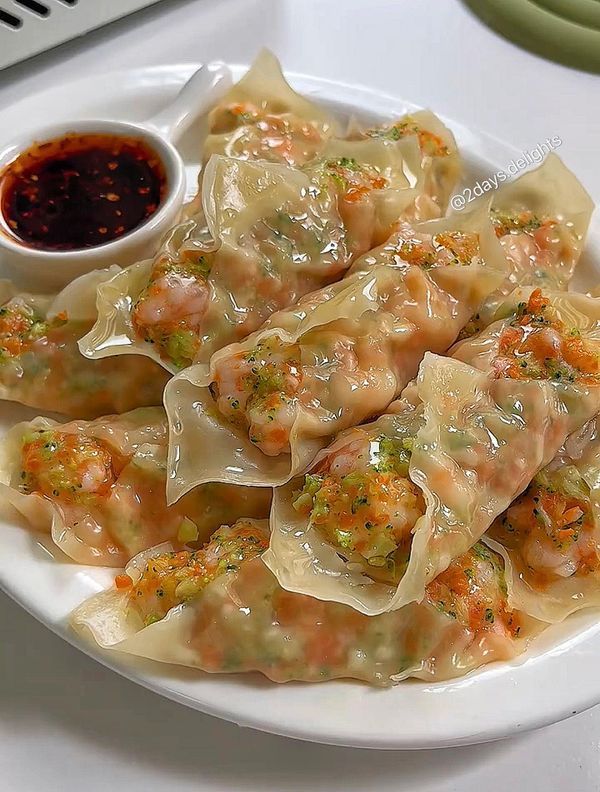 a white plate topped with dumplings covered in sauce