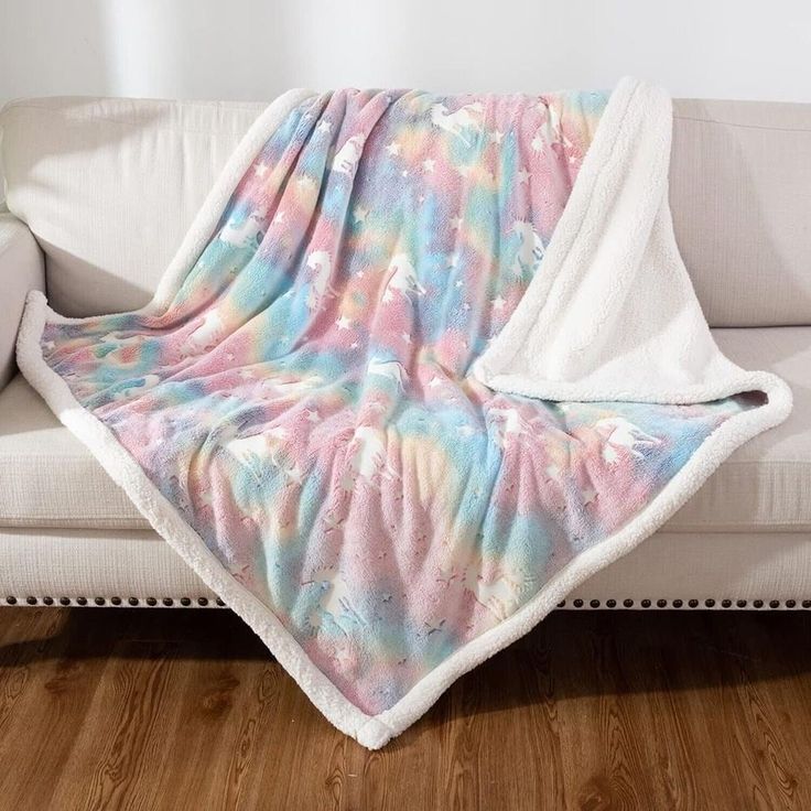 a white couch with a pink and blue tie dye blanket on it's back