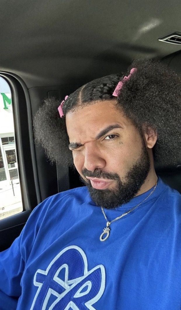 a man sitting in the back seat of a car with an afro on his head