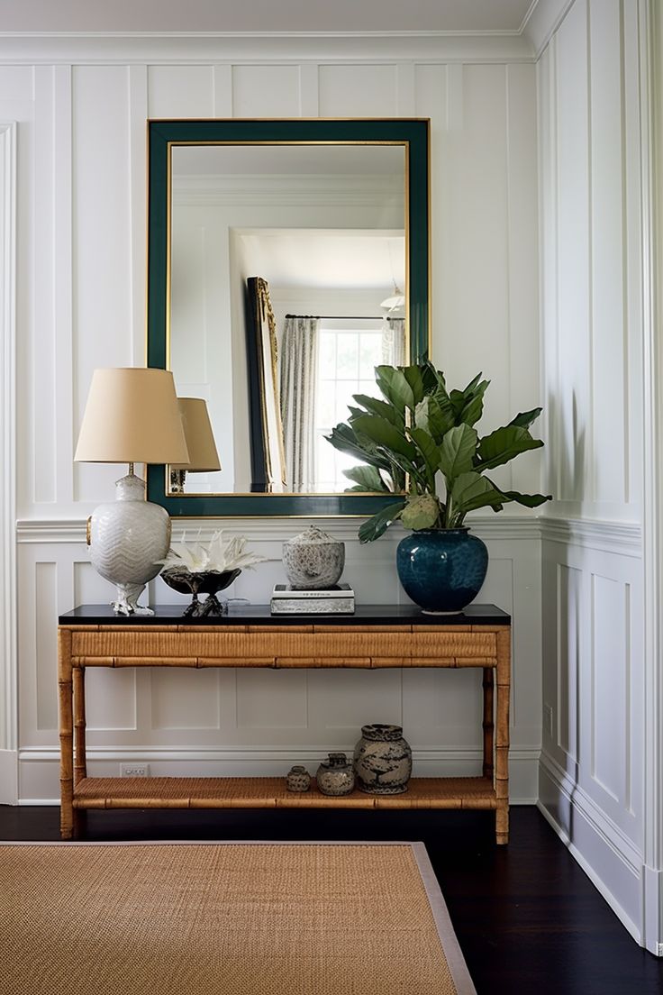 a table with a mirror, lamp and vase on it next to a rug in a room