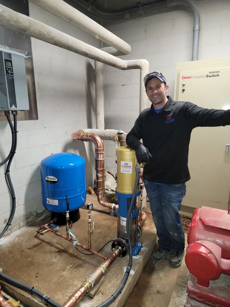 a man standing next to a water heater in a room with pipes and piping