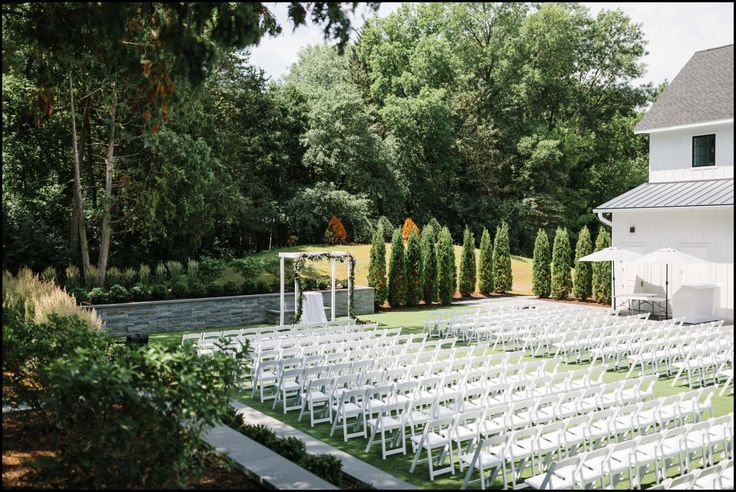 an outdoor ceremony set up with white chairs