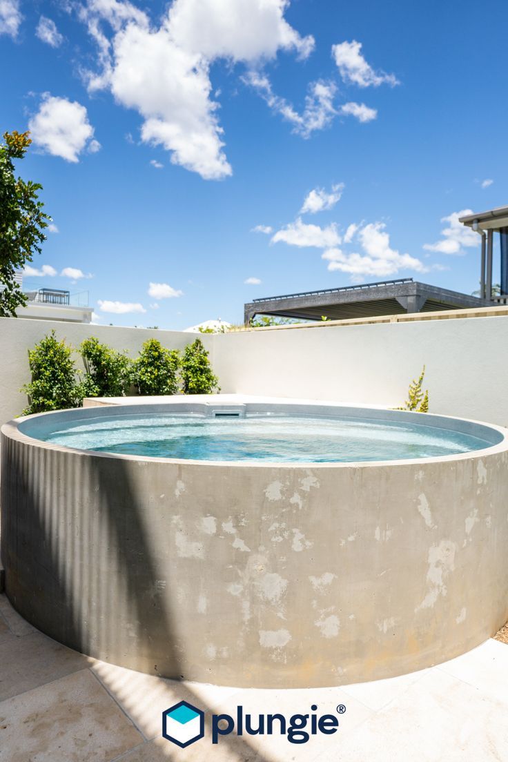 an outdoor hot tub in the middle of a patio with blue sky and clouds above it