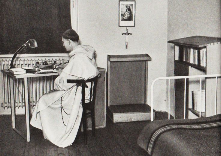 a woman sitting at a desk in front of a blackboard with writing on it