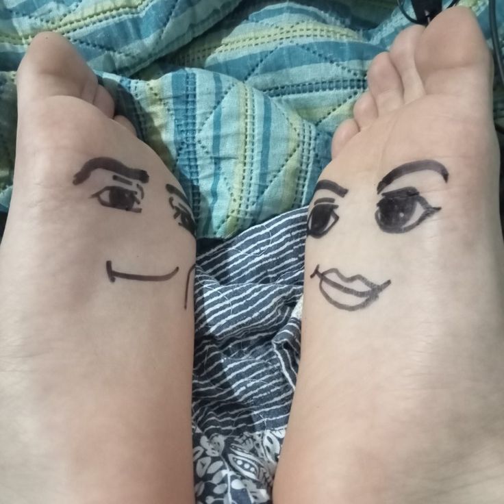 two people with faces drawn on their arms and legs, both have black ink painted on them