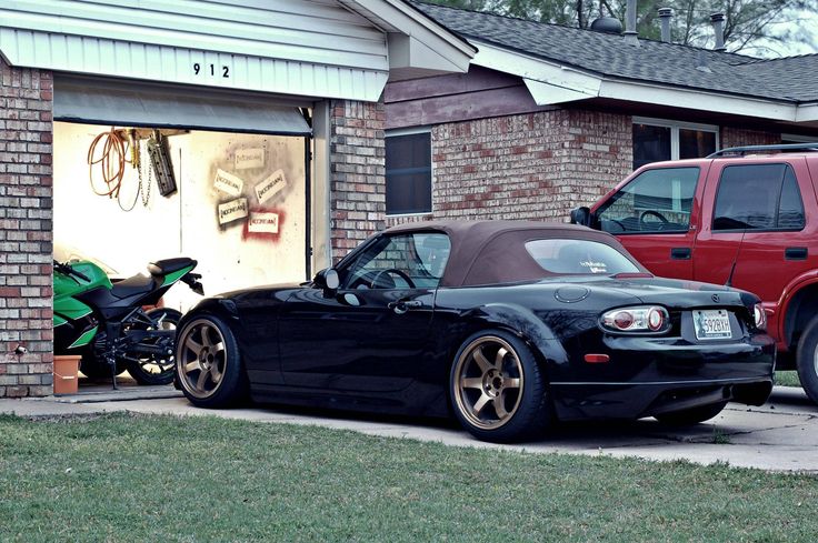 a black sports car parked in front of a garage with its hood up and the door open