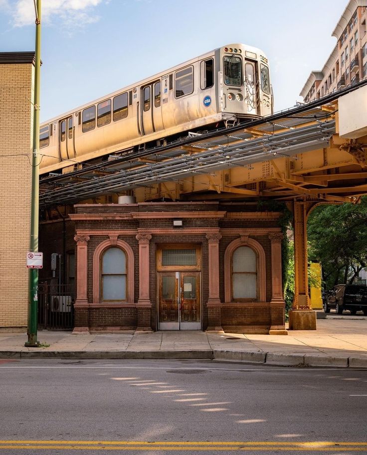 the train is going over the top of the building on the tracks above the street