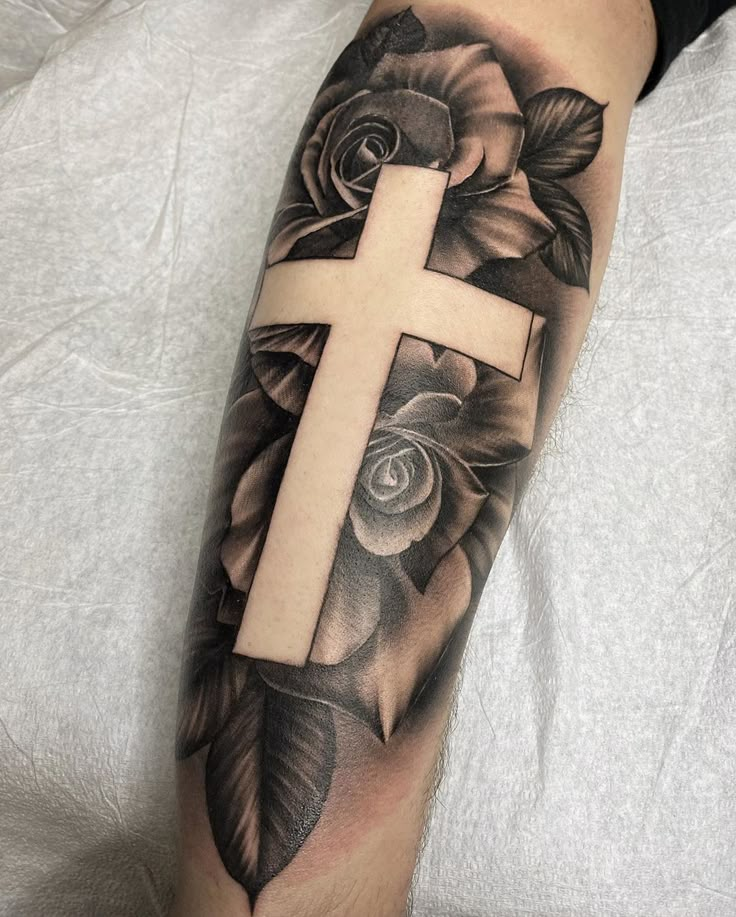 a cross with roses and leaves on the arm is shown in black and grey colors