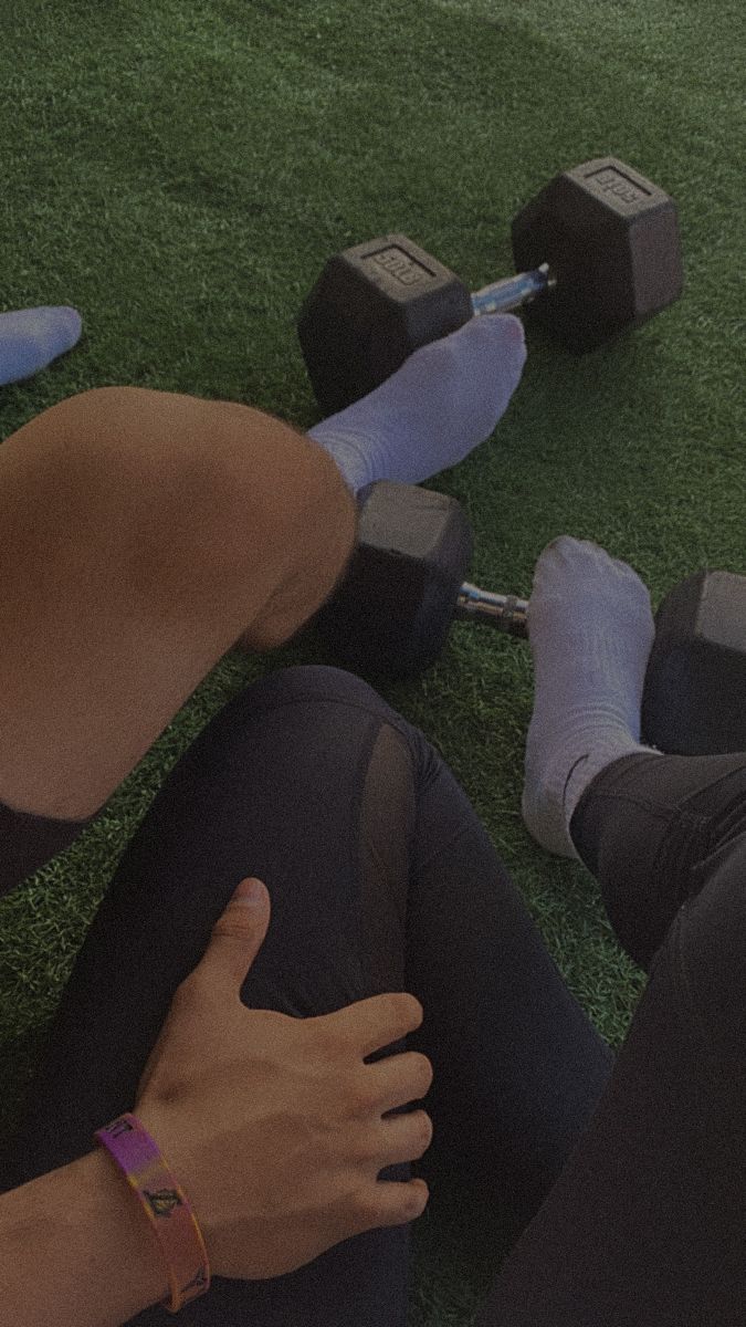 a woman laying on the ground with her legs crossed and two dumbbells behind her