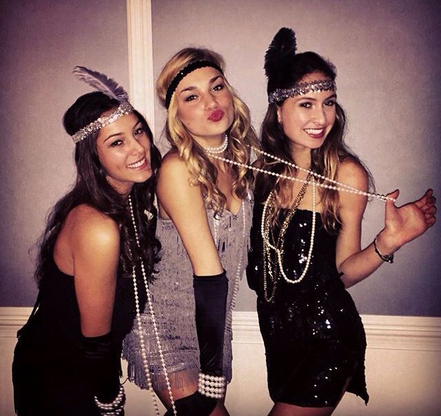 three beautiful young women standing next to each other wearing headbands and feathers on their heads