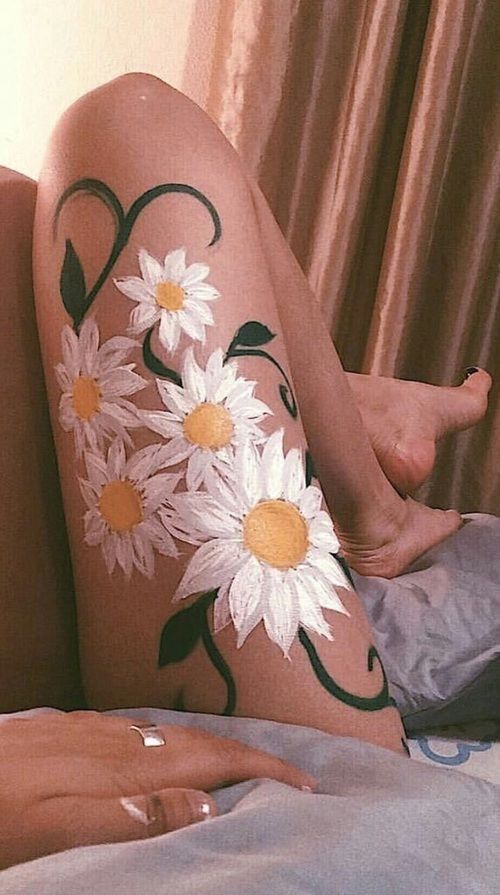 a woman with white flowers painted on her leg